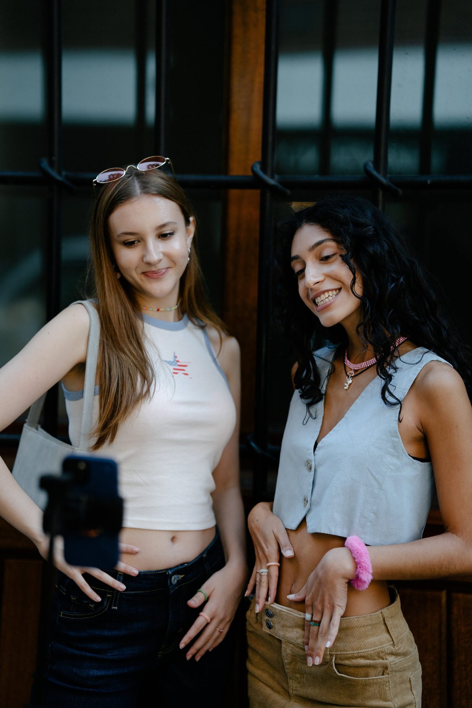 Young Fashionable Girls Taking a Picture with a Smartphone on a Tripod